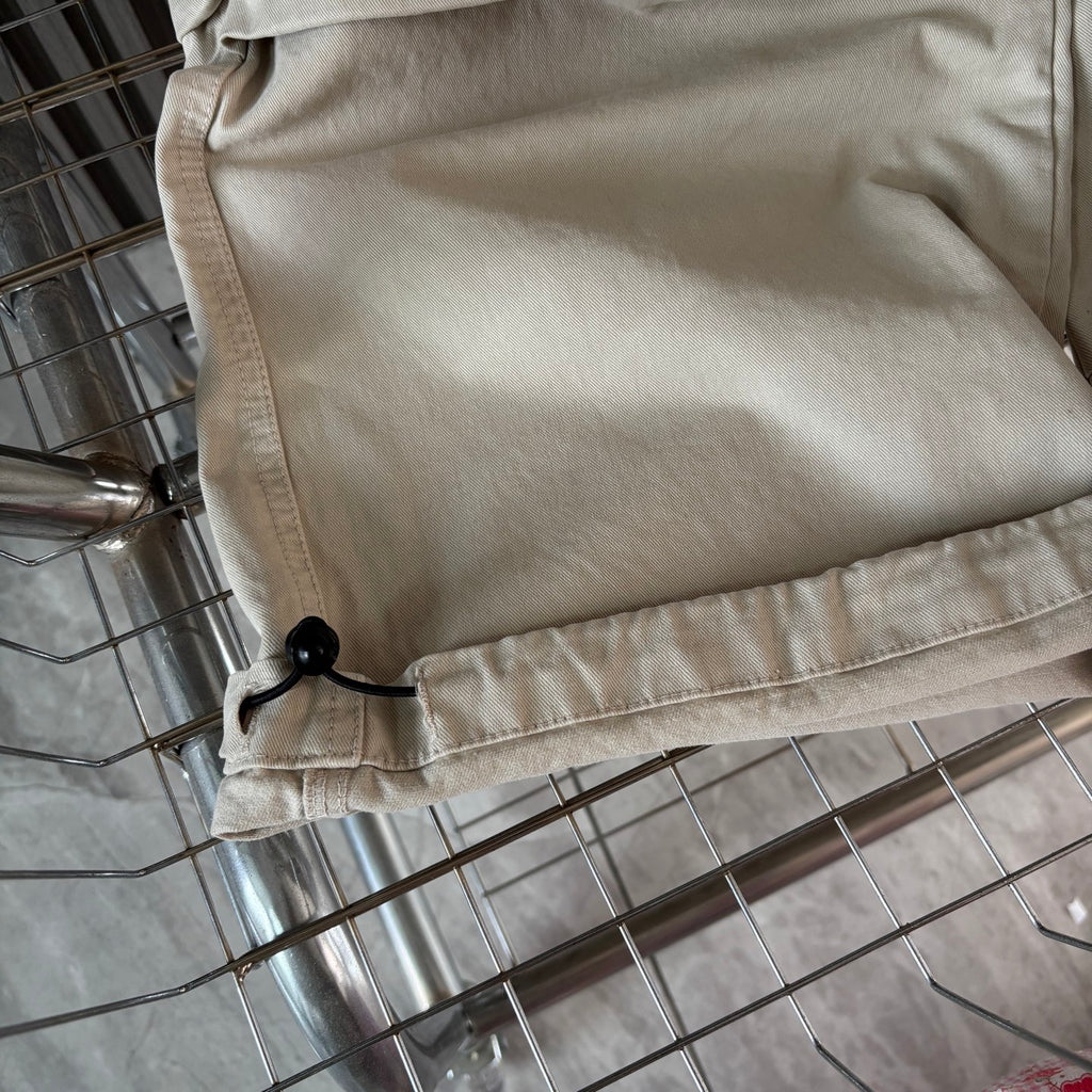 Cream cargo shorts close-up with side button detail and stitched hem