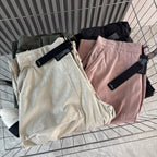 Cargo shorts folded on display in cream, pink, olive, and dark gray