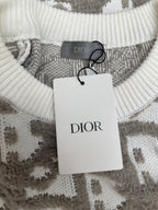 Crew-neck ribbed knit sweater with DIOR tag hanging on gray and white logo-like pattern