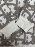 Close-up of knit sweater cuffs and hem in white ribbing on gray logo-like pattern