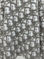 Close-up of gray and white knit sweater with repeating logo-like pattern