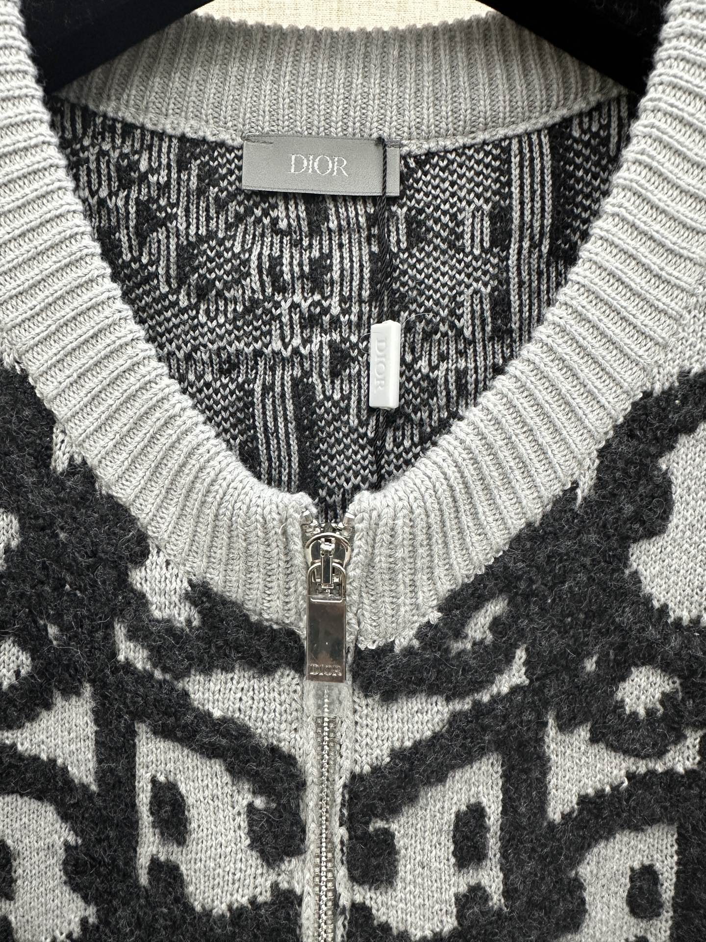 Dior jacquard knit cardigan close-up, metal zipper and ribbed V-neck, dark/white