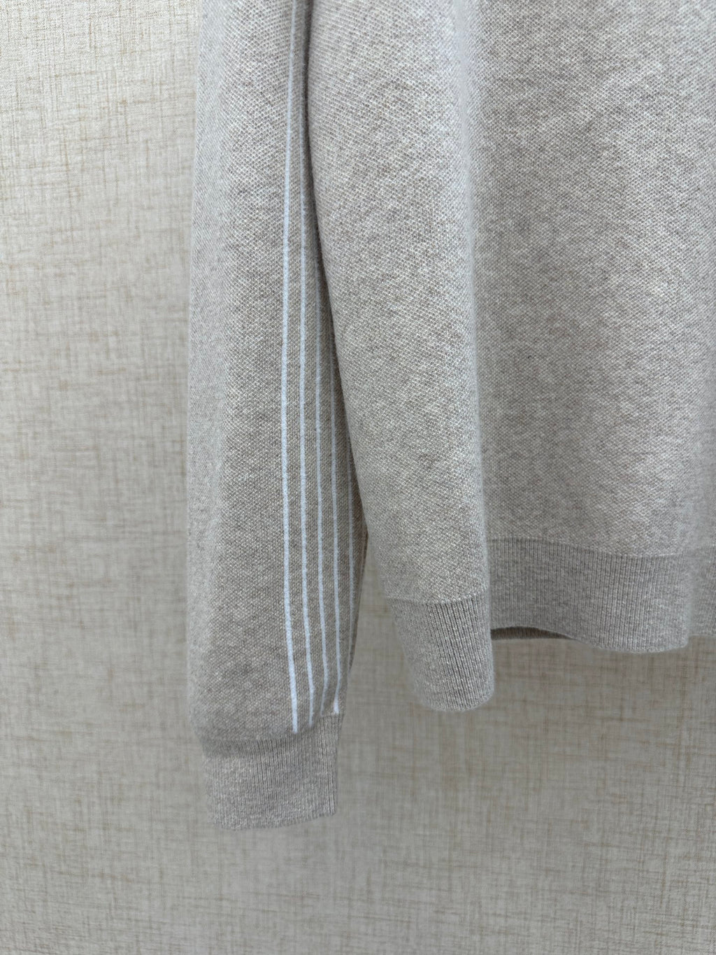 Beige long-sleeve hoodie sleeve with white vertical stripe trim at cuff