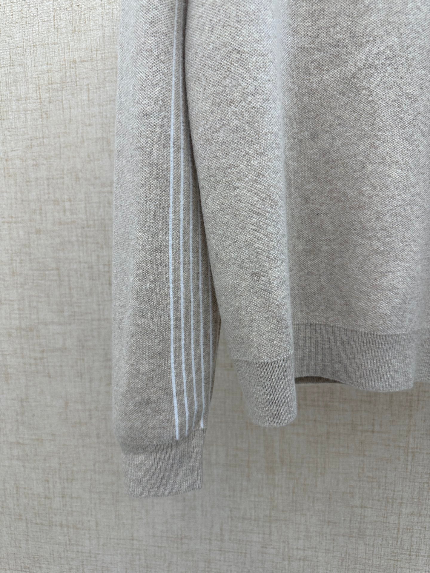 Beige long-sleeve hoodie sleeve with white vertical stripe trim at cuff