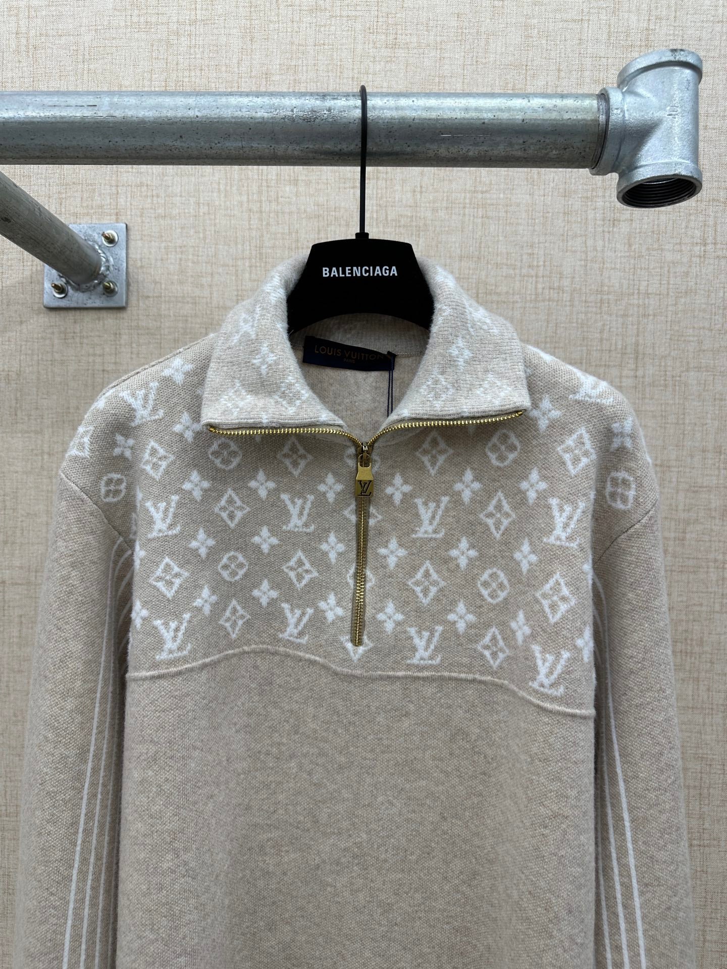 Beige hoodie with white monogram band, front half-zip and gold zipper pull