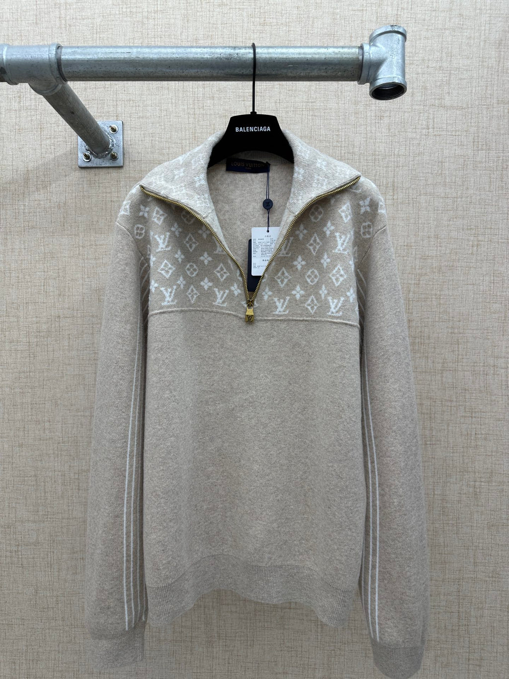 Beige long-sleeve hoodie with white monogram pattern and front zip