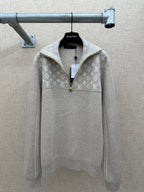 Beige long-sleeve hoodie with white monogram pattern and front zip