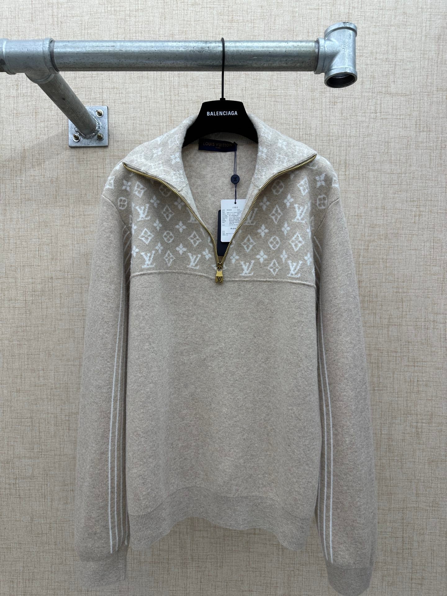 Beige long-sleeve hoodie with white monogram pattern and front zip