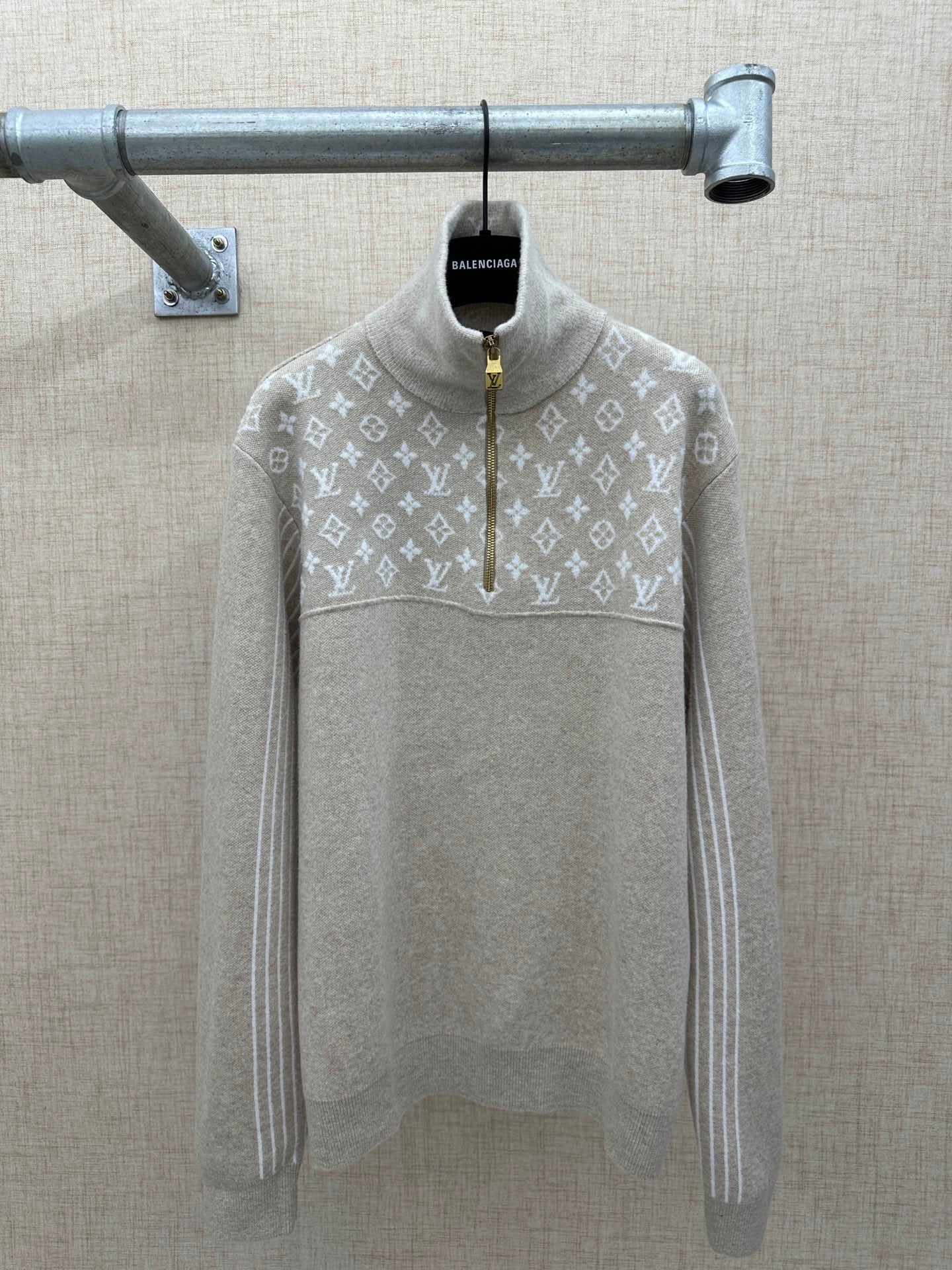 Beige long-sleeve hoodie back with white monogram pattern and front half-zip