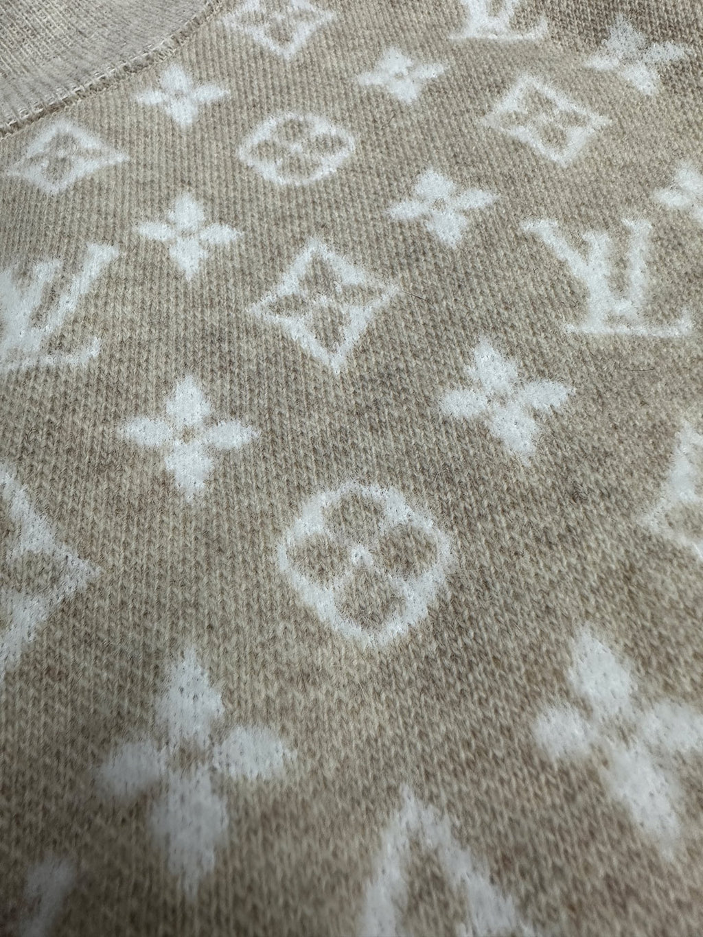 Long-sleeve top close-up with light gray knit and white monogram-style pattern
