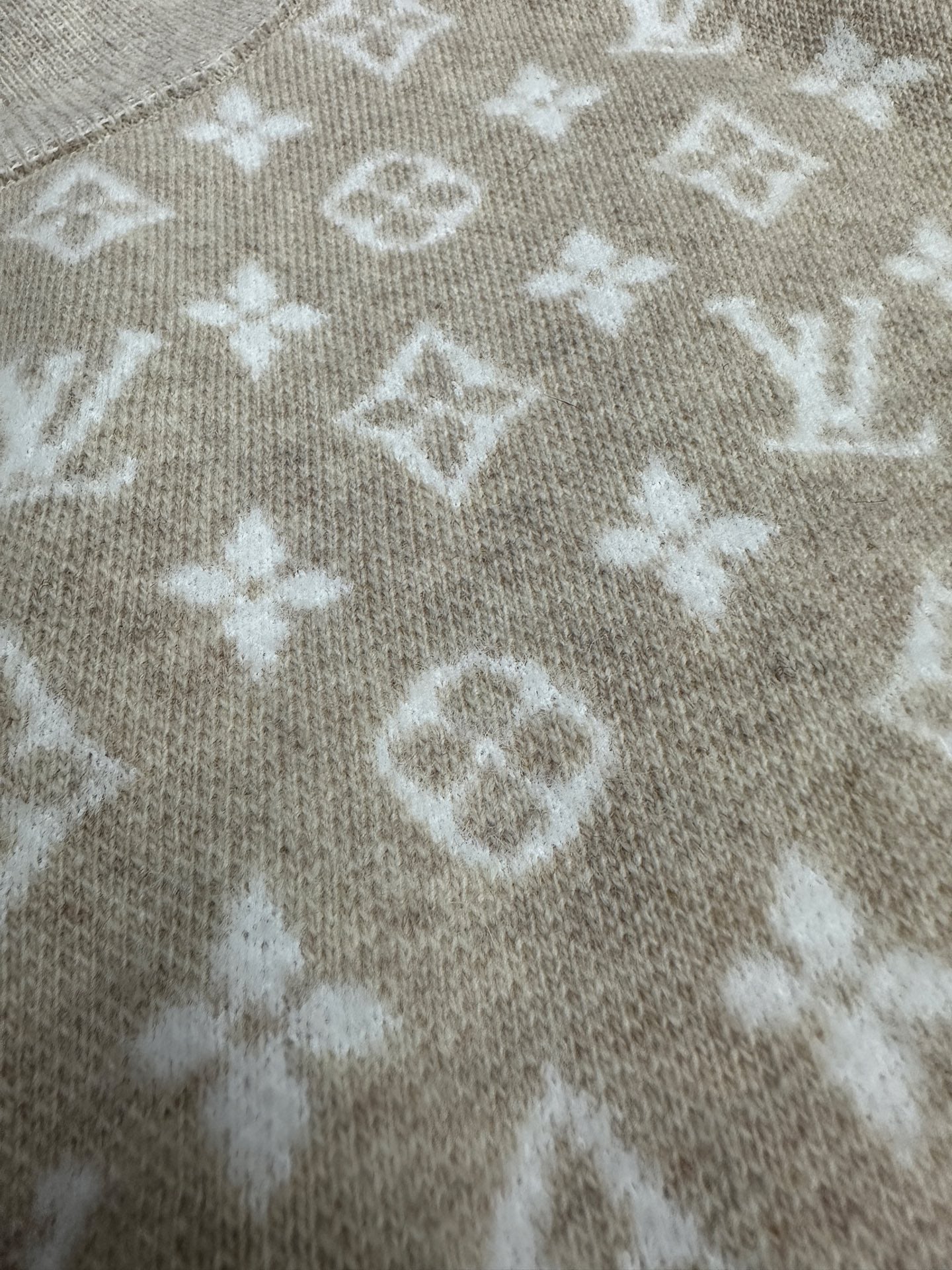 Long-sleeve top close-up with light gray knit and white monogram-style pattern