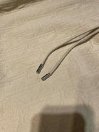 Cream hoodie drawstrings with metal tips on textured fabric