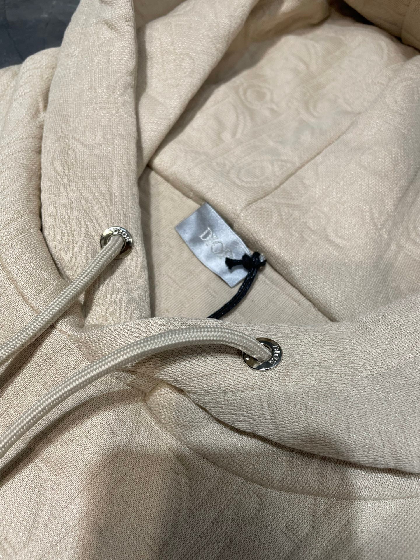 Cream embossed hoodie fabric with drawstring cords and metal aglets