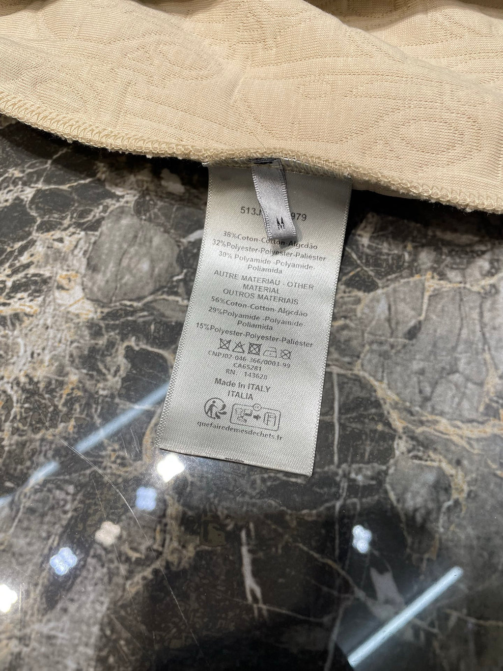Inside label on cream hoodie with care details and Made in Italy