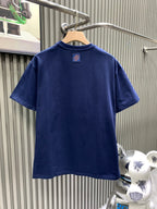 Blue T-shirt back view with small neck logo patch at center.