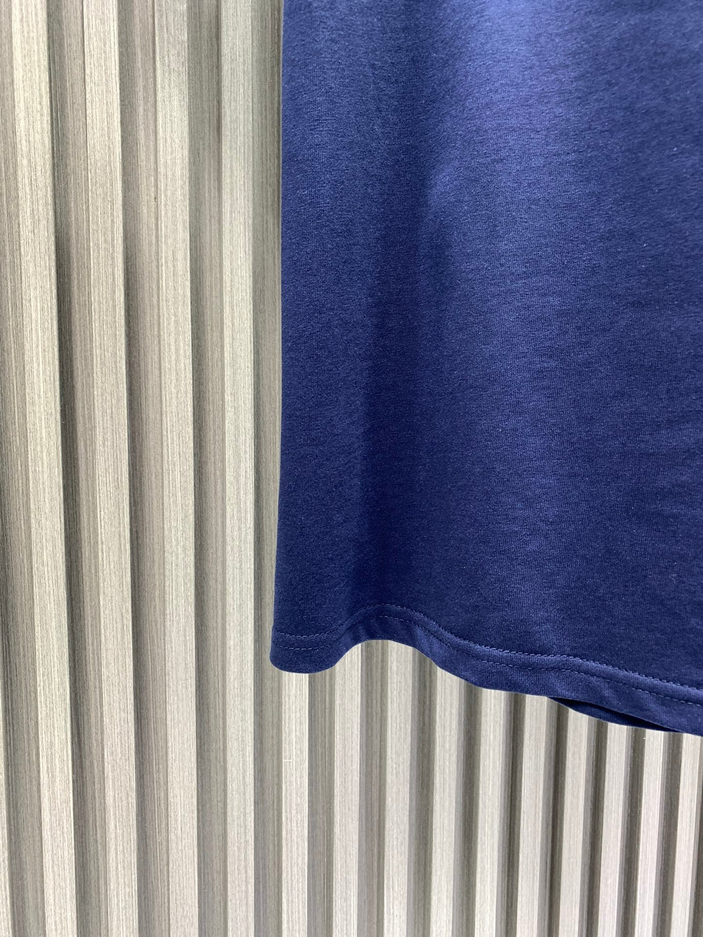 Blue T-shirt hem detail with curved bottom edge.