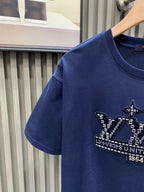 Blue T-shirt with embroidered crown graphic on chest, short sleeves.