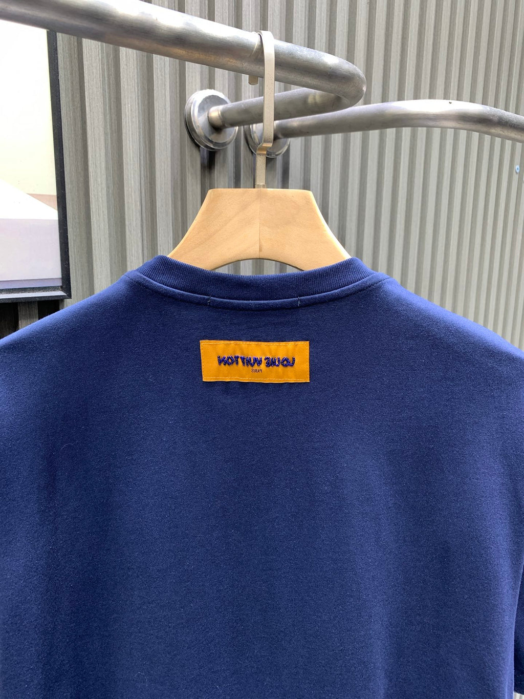 Navy short-sleeve T-shirt with yellow brand label at upper back