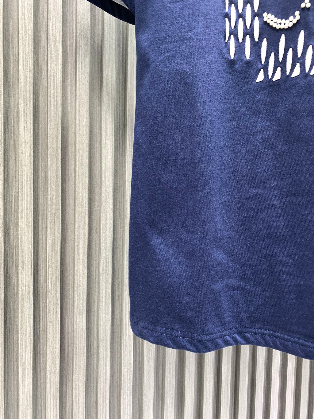 Navy short-sleeve T-shirt hem detail with logo partially visible