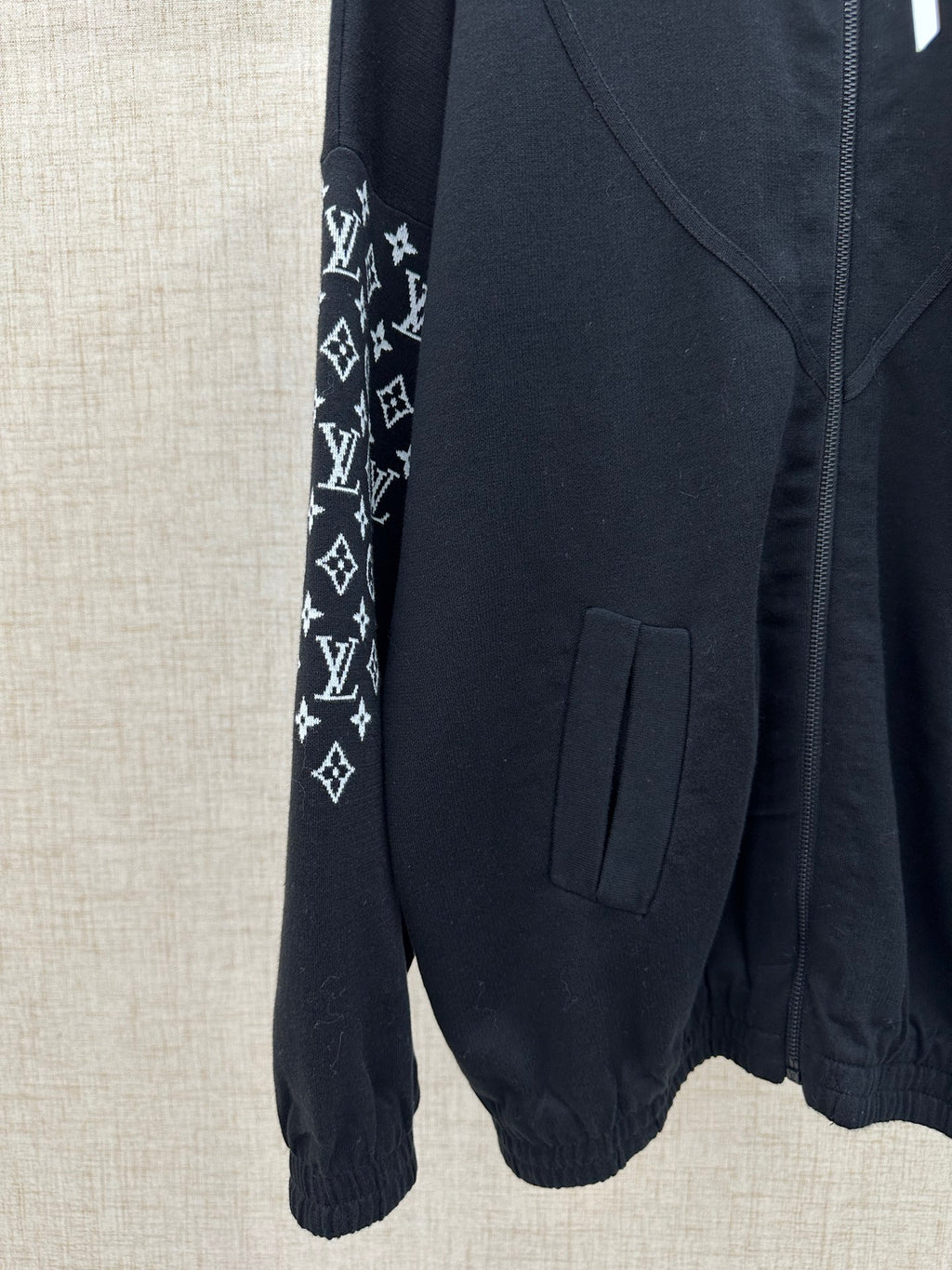 Black jacket sleeve with logo-print panel and patch pocket at hip