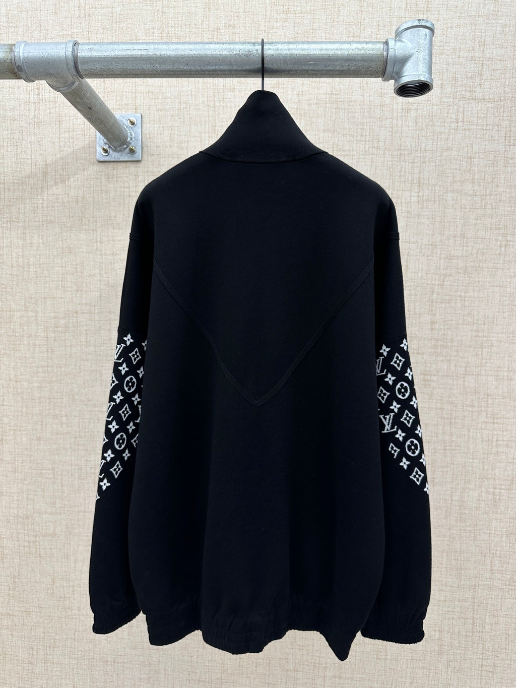 Black back view jacket with high collar and logo-print sleeve panels