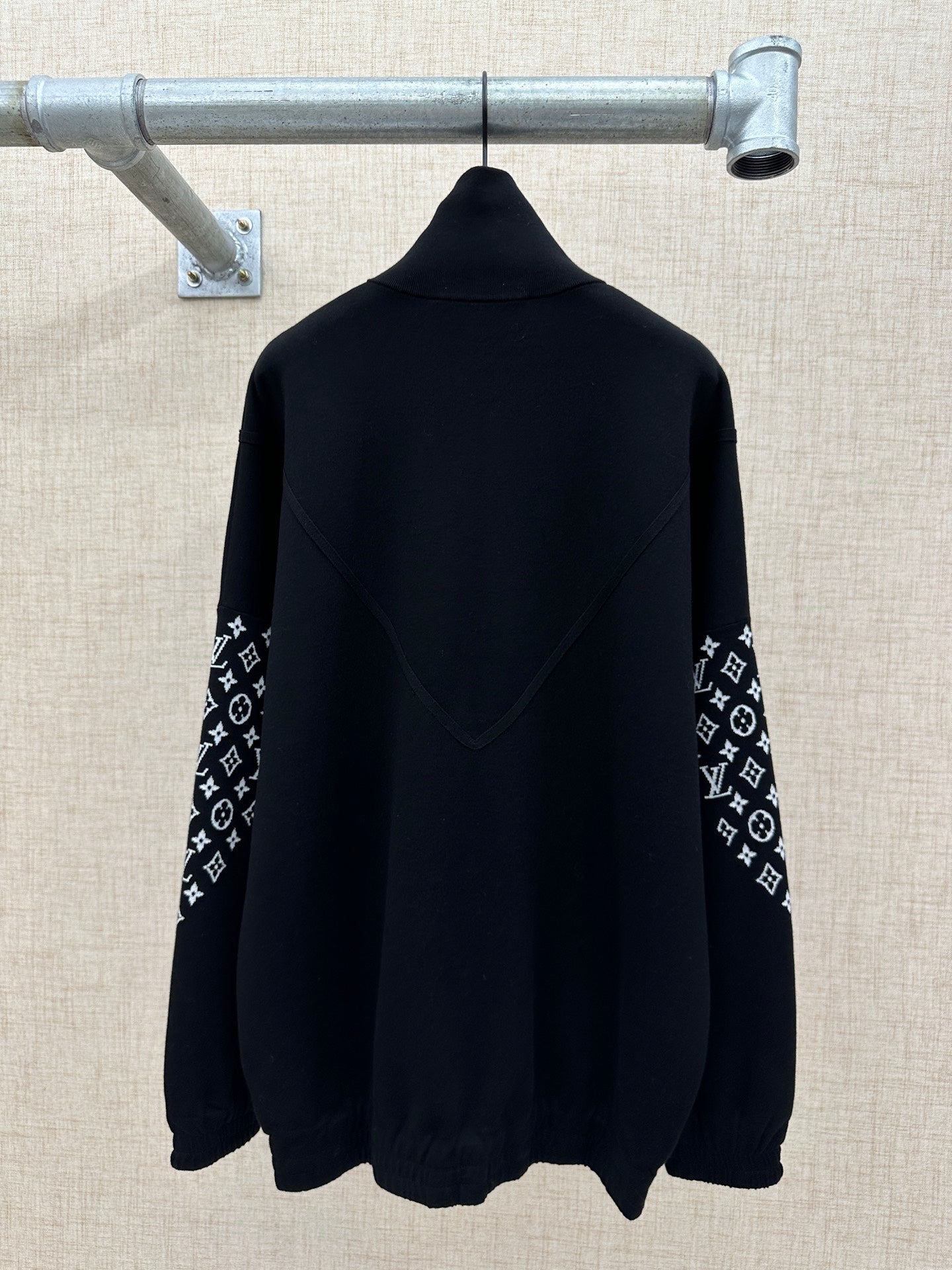 Black back view jacket with high collar and logo-print sleeve panels