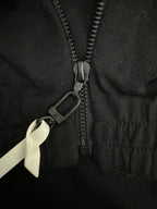 Black jacket zipper pull with small logo charm and ribbon tie