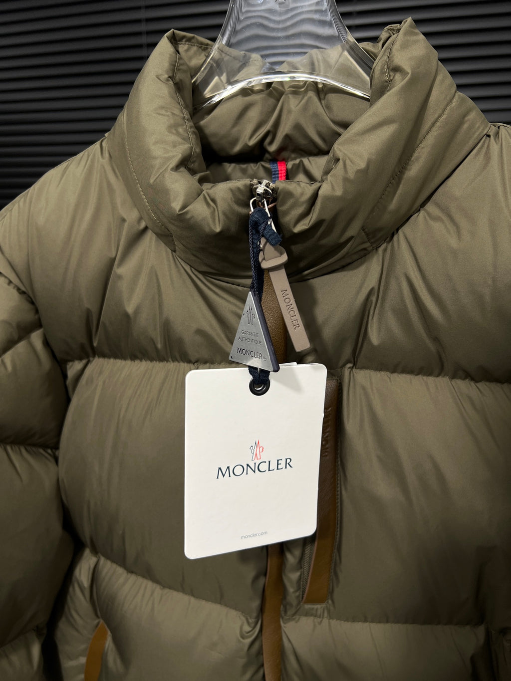 Long puffer jacket with olive quilted panels and interior lining view, zip center