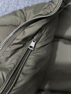 Puffer jacket close-up of metal zipper pull and olive fabric with snap tag