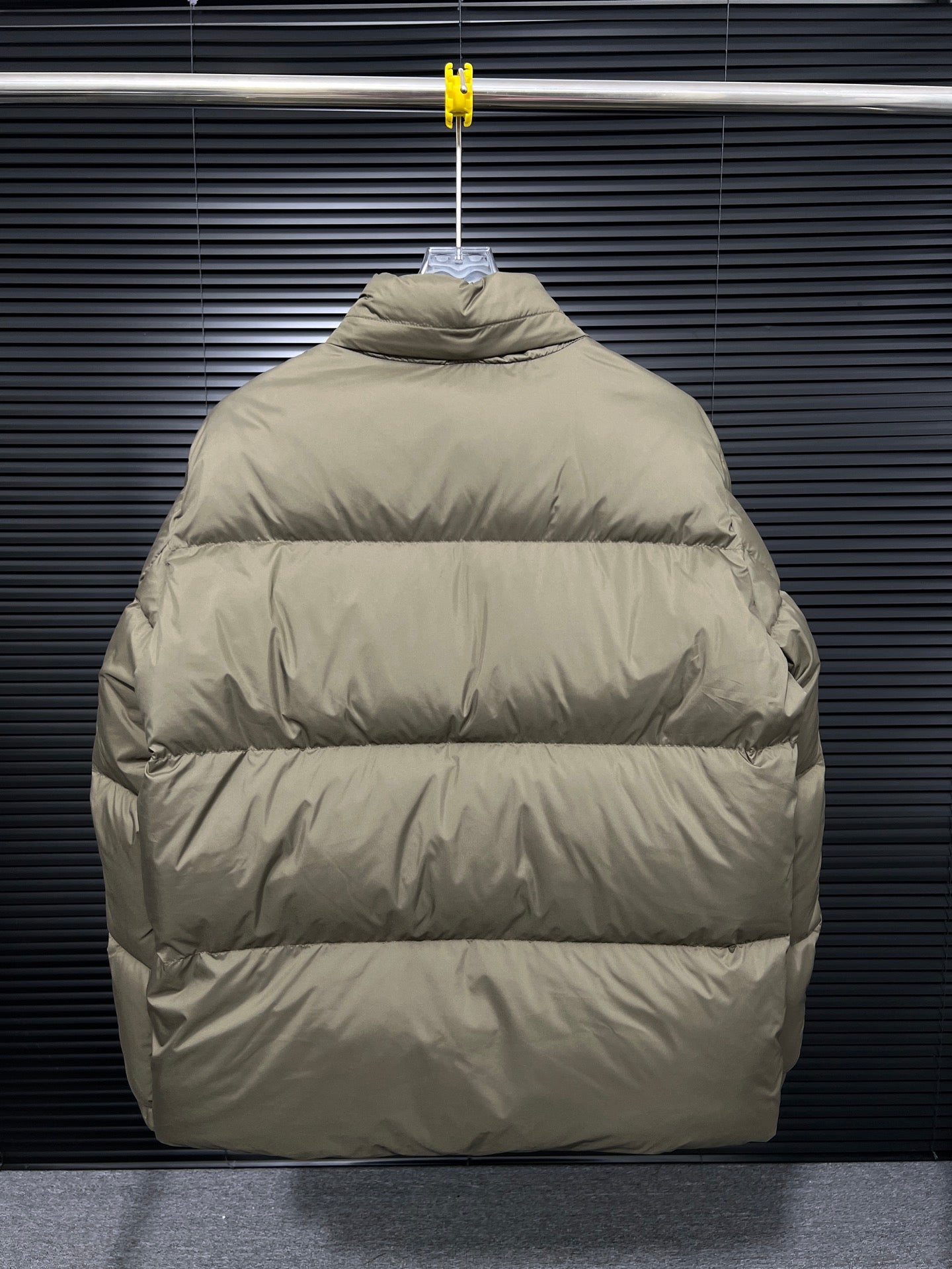 Long puffer jacket back view with hood, hanging on a hanger