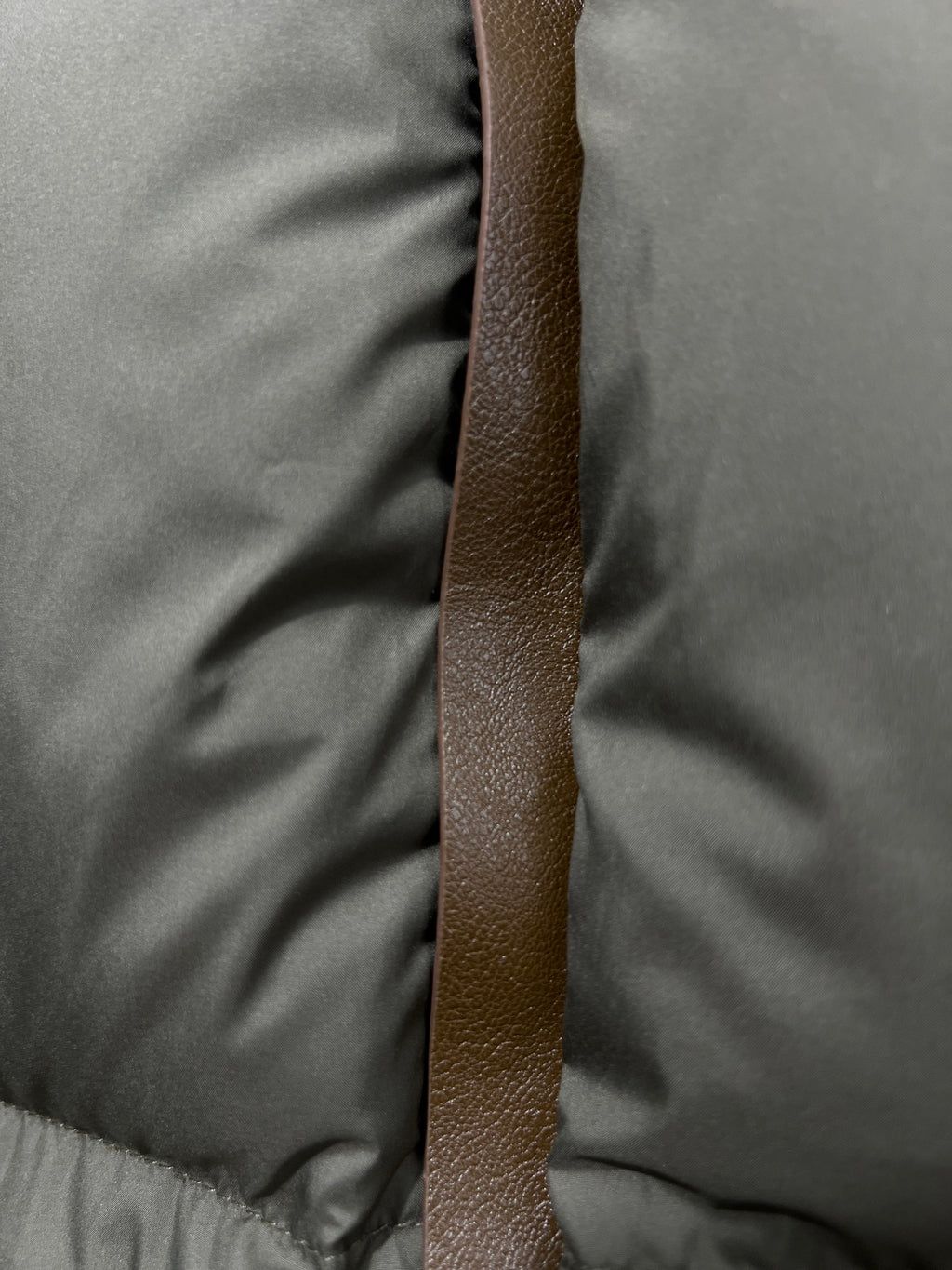 Puffer jacket vertical brown leather-look strap detail on olive quilted fabric