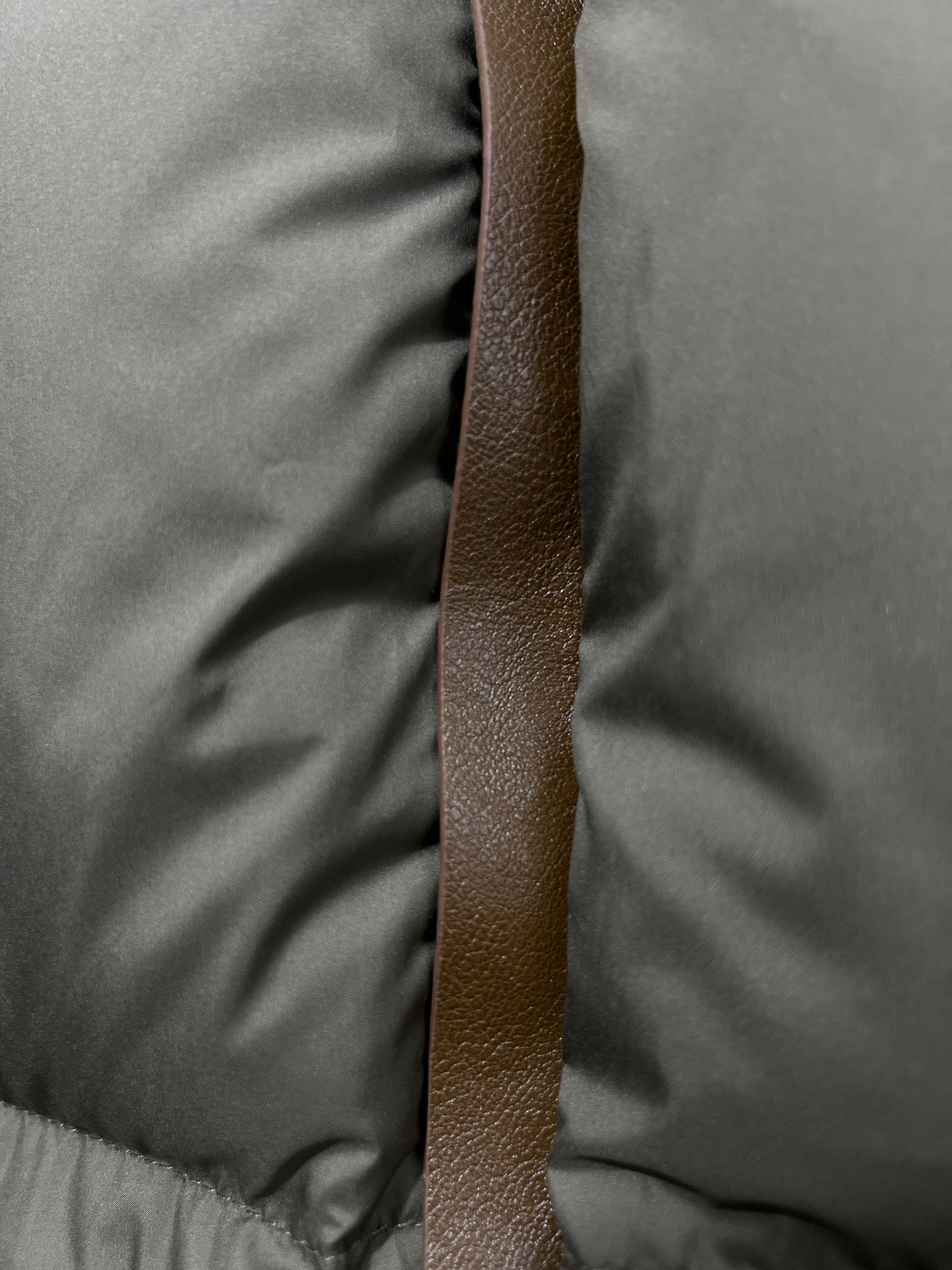 Puffer jacket vertical brown leather-look strap detail on olive quilted fabric
