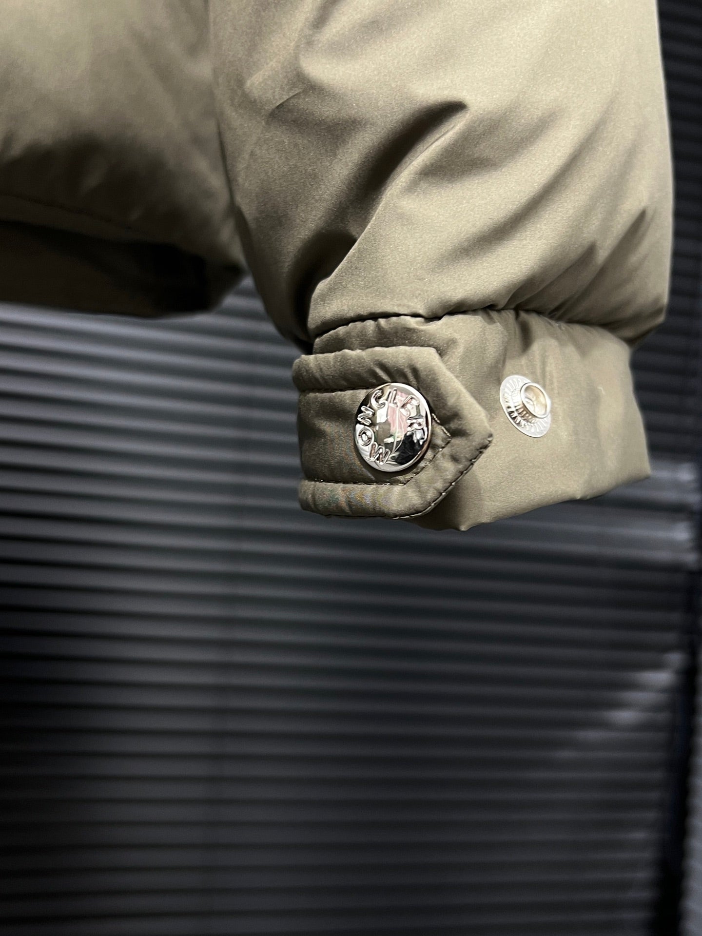 Puffer jacket cuff with round logo patch and small snap-button tab