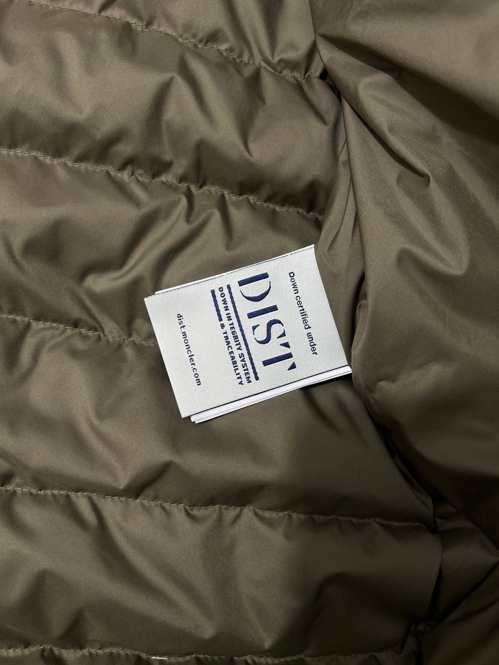 Olive puffer jacket with white brand and care label inside
