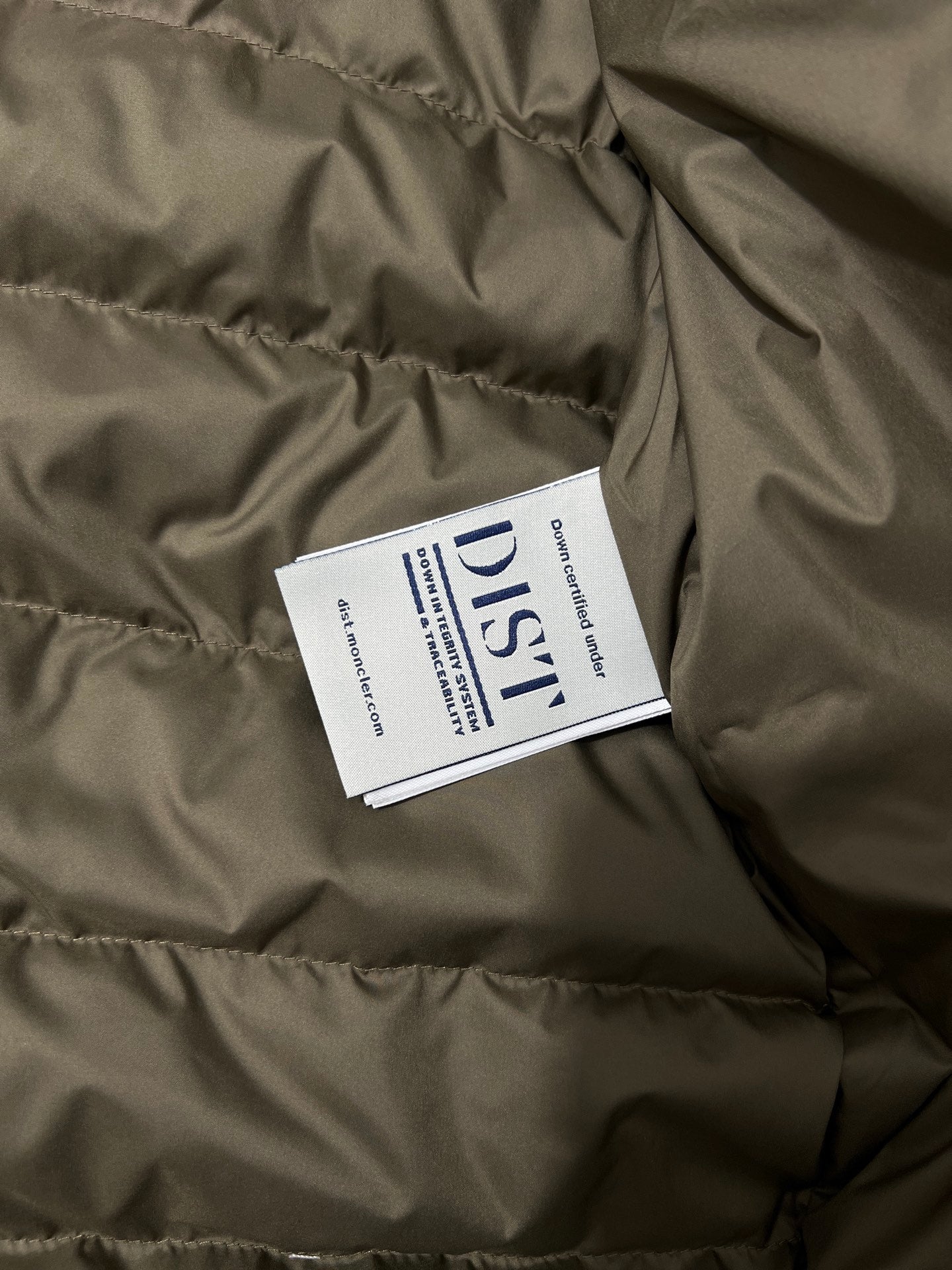 Olive puffer jacket with white brand and care label inside