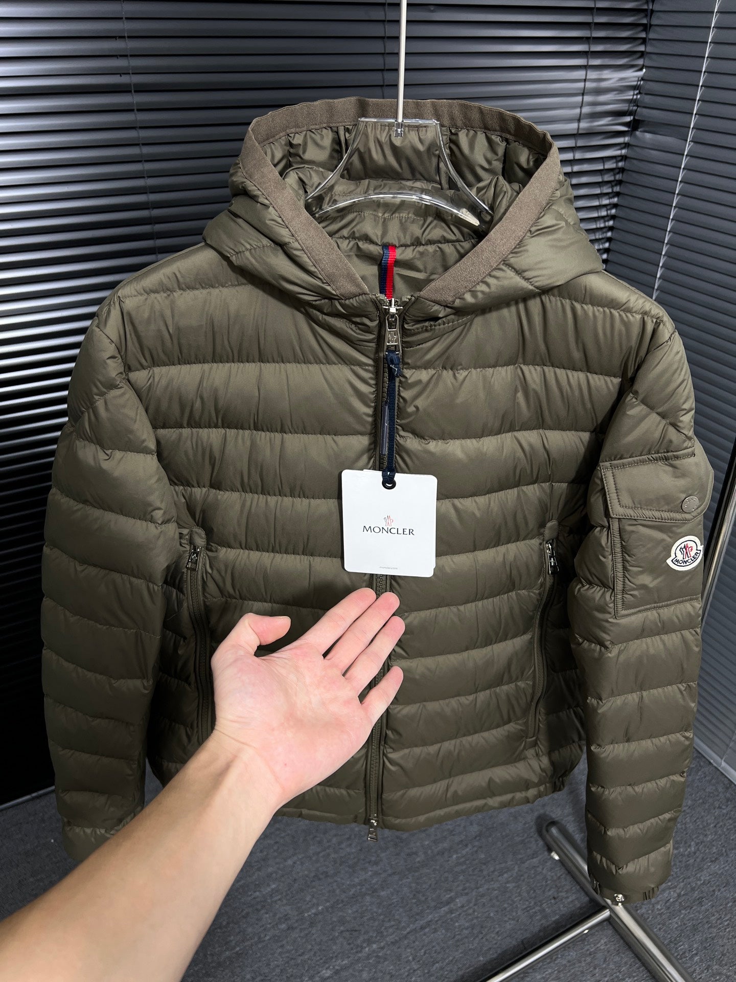 Olive hooded puffer jacket with front zipper and hang tag