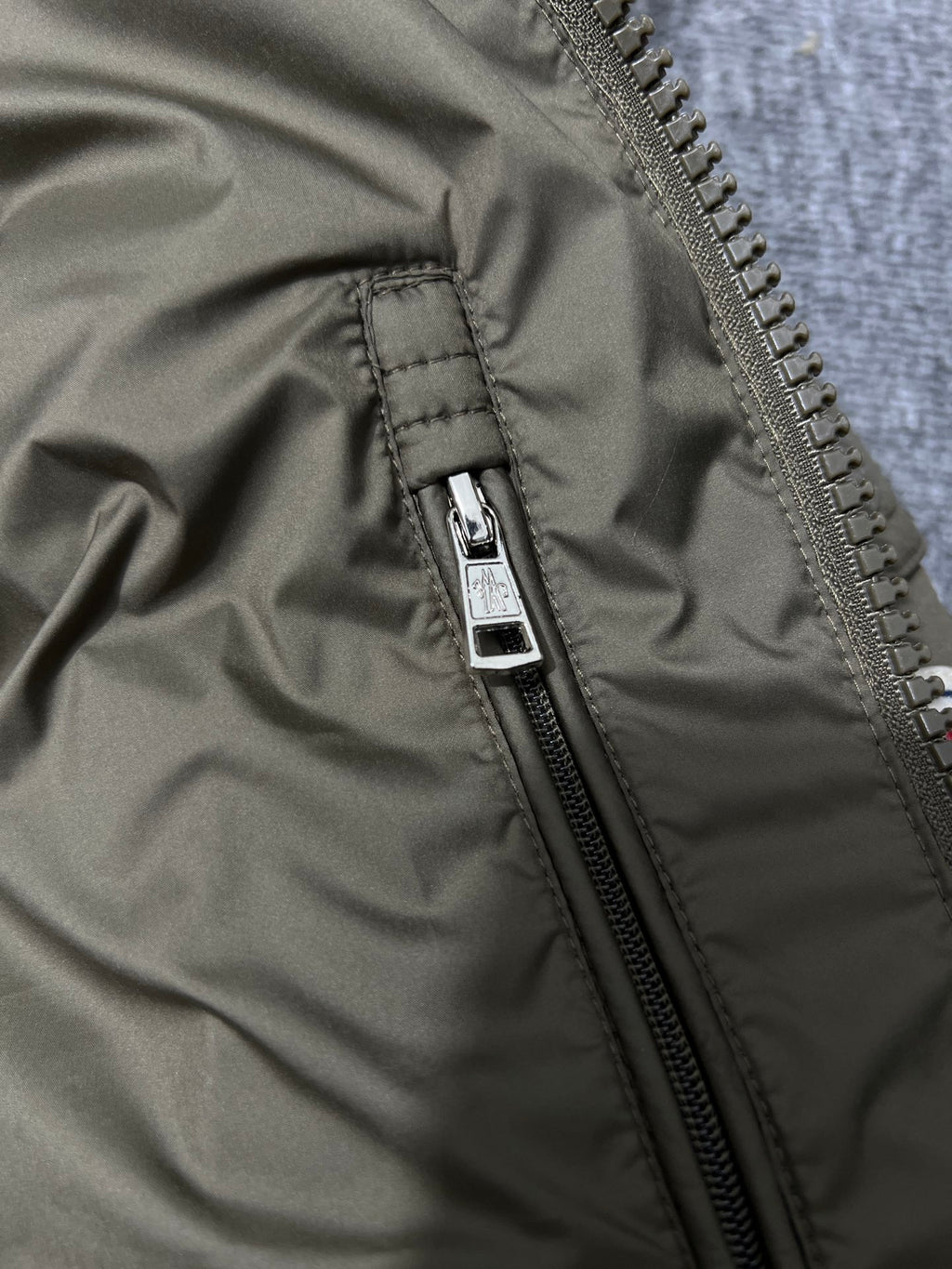 Olive puffer jacket front zipper seam and pull tab