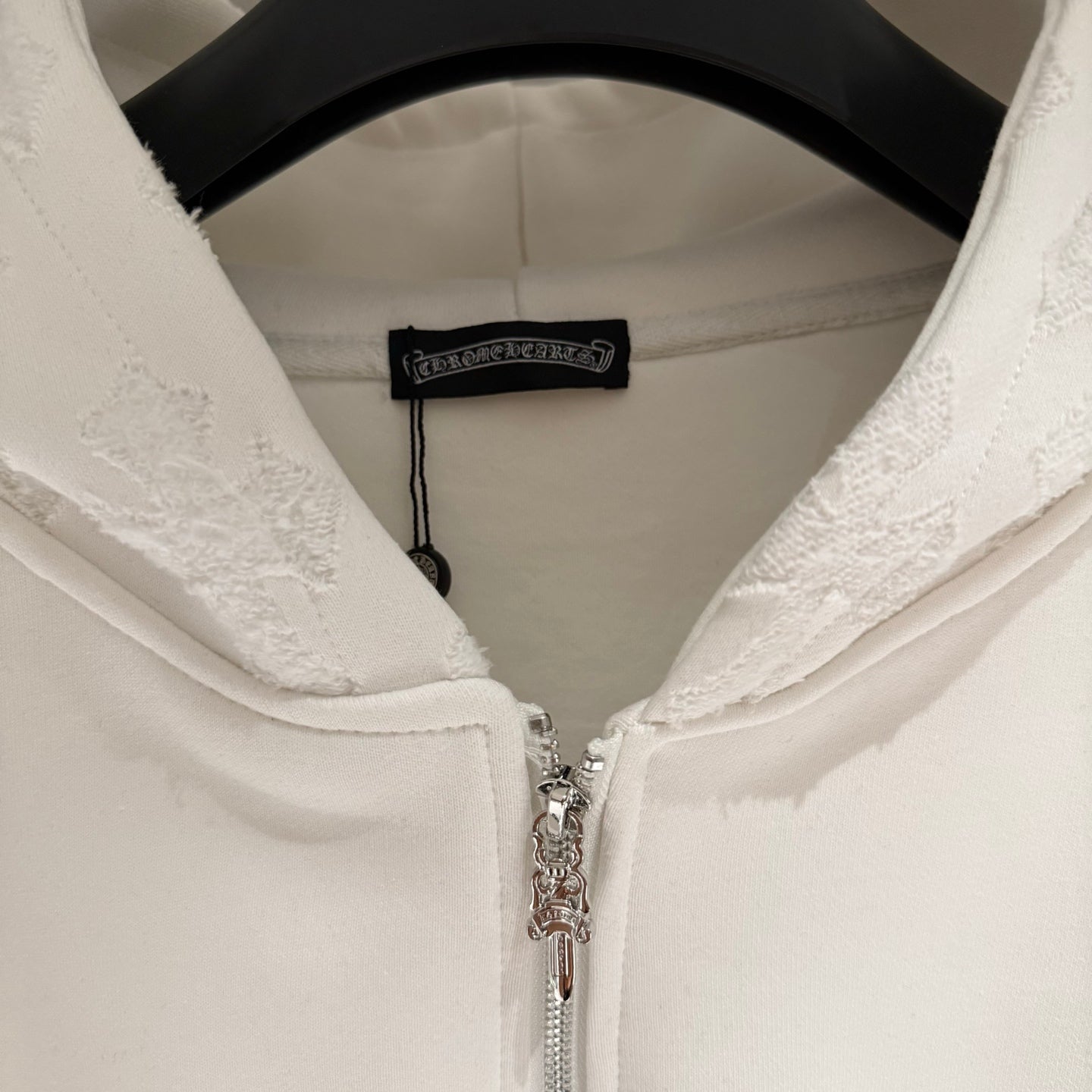 White hoodie neck with hood lining, zipper pull, and small brand label