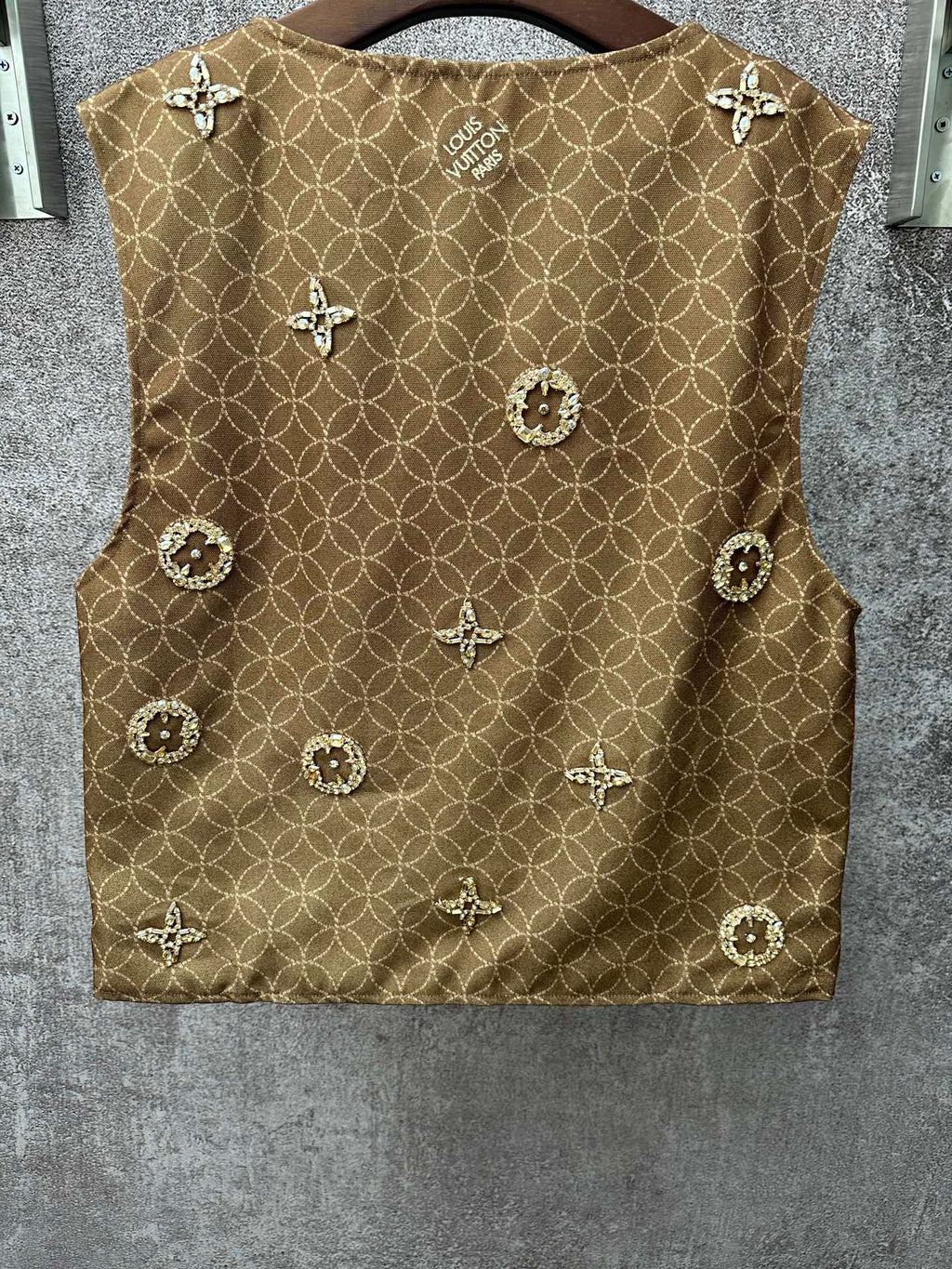 Gold monogram sleeveless vest with decorative medallions, back view close-up