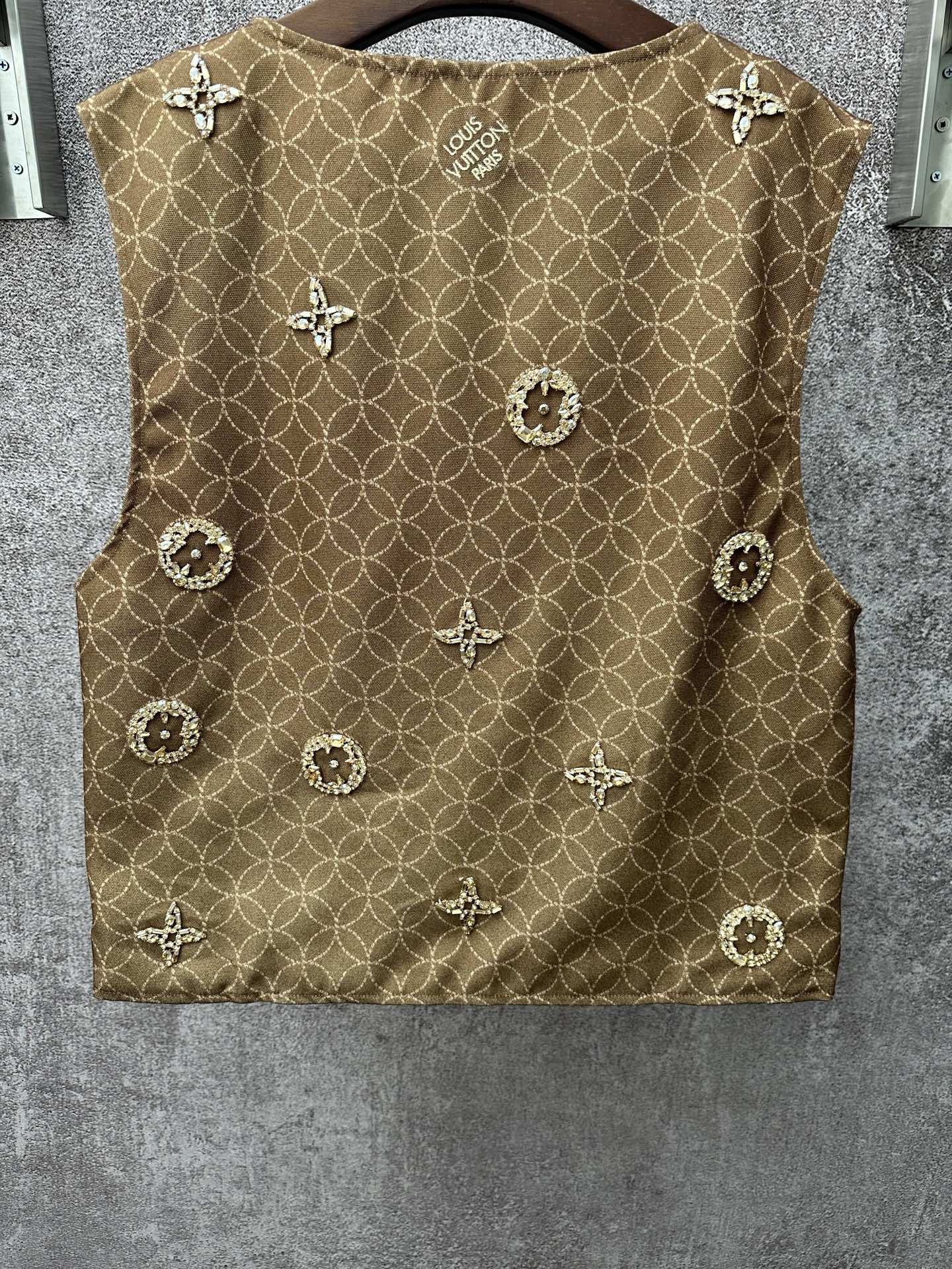 Gold monogram sleeveless vest with decorative medallions, back view close-up