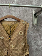 Gold monogram sleeveless vest with zip front, stitched collar, and decorative shoulder charm