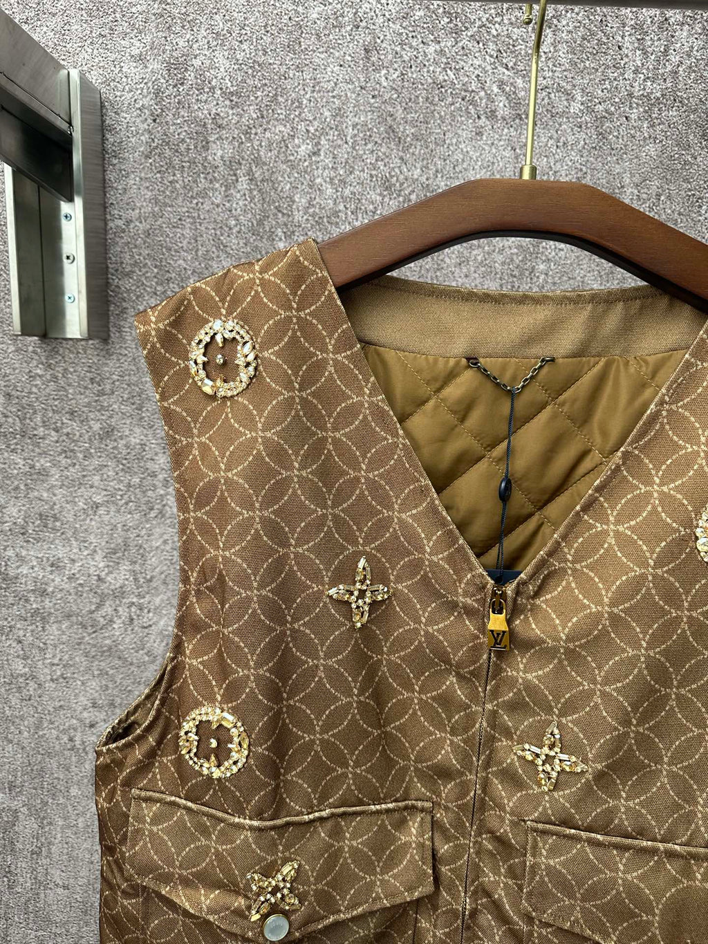 Gold monogram sleeveless vest with zip front and round embellished pocket flaps