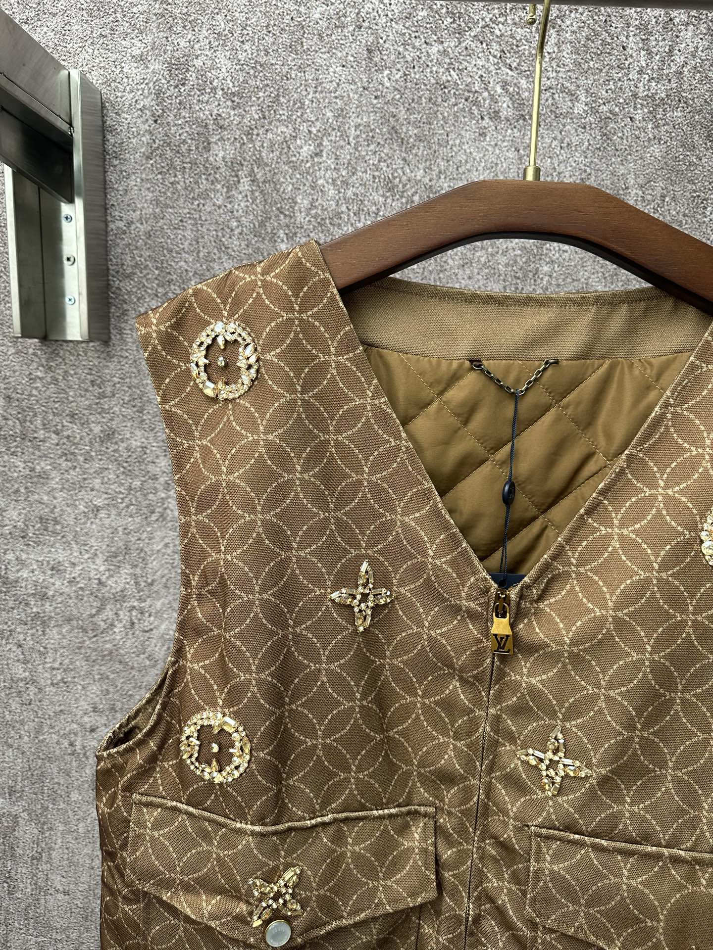 Gold monogram sleeveless vest with zip front and round embellished pocket flaps