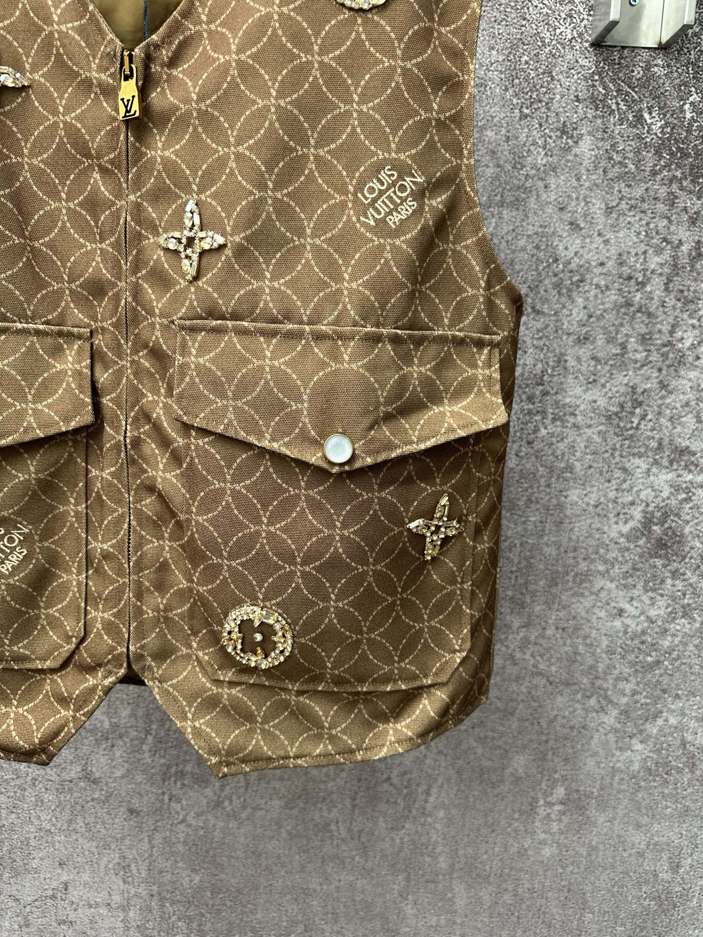 Gold monogram sleeveless vest with flap pockets and round decorative buttons, side view
