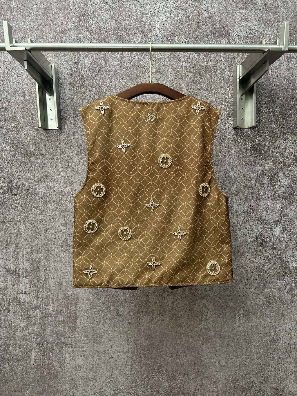 Gold monogram sleeveless vest with round decorative embellishments on front panel