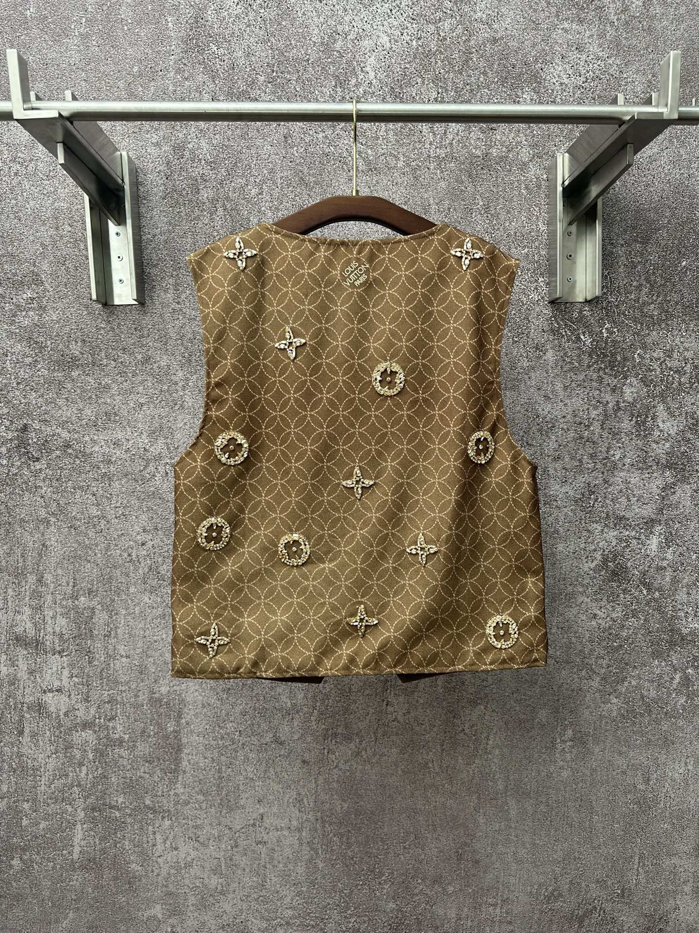 Gold monogram sleeveless vest with round decorative embellishments on front panel