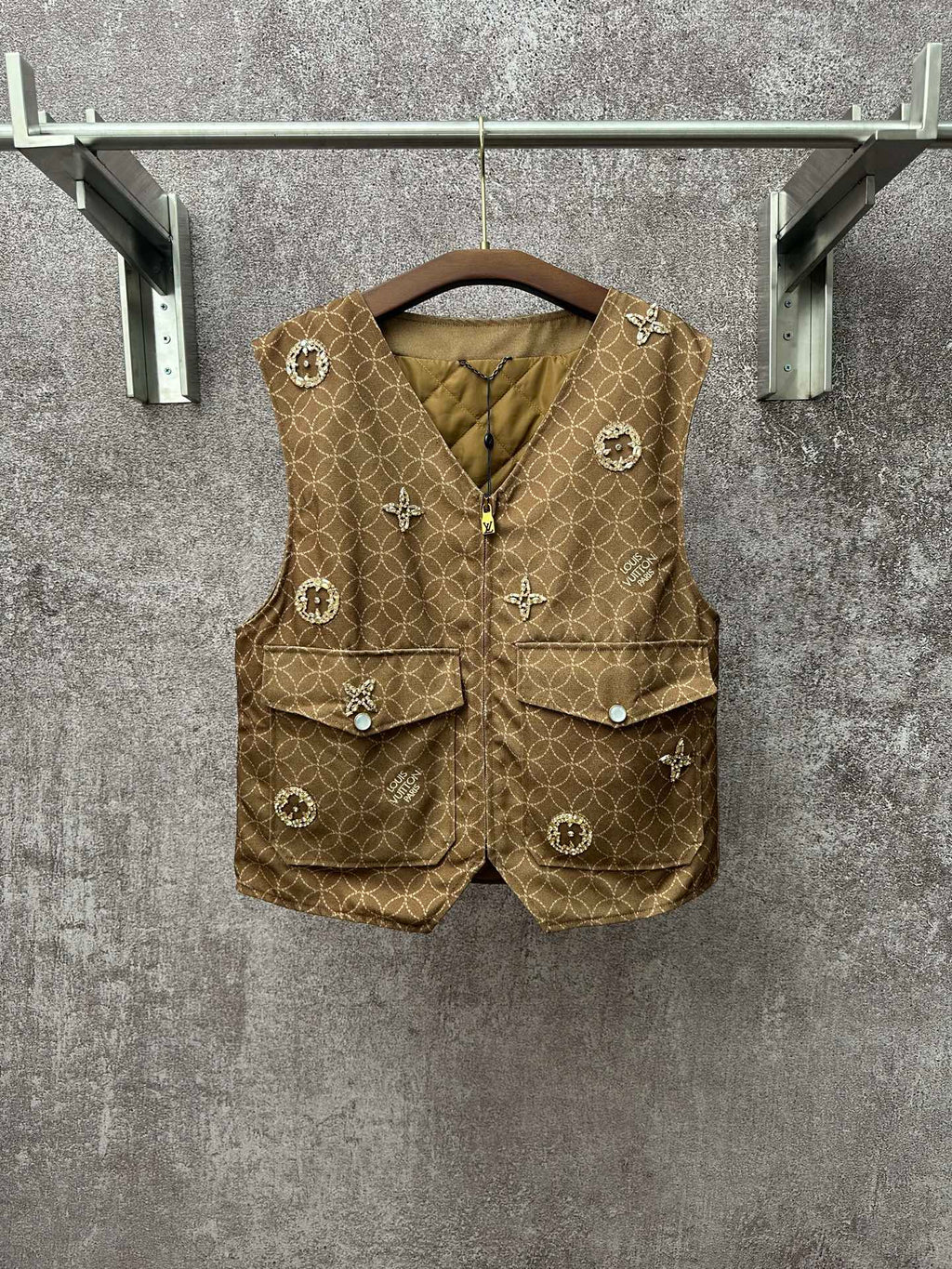 Gold monogram sleeveless vest with zip front, flap pockets, decorative charm buttons