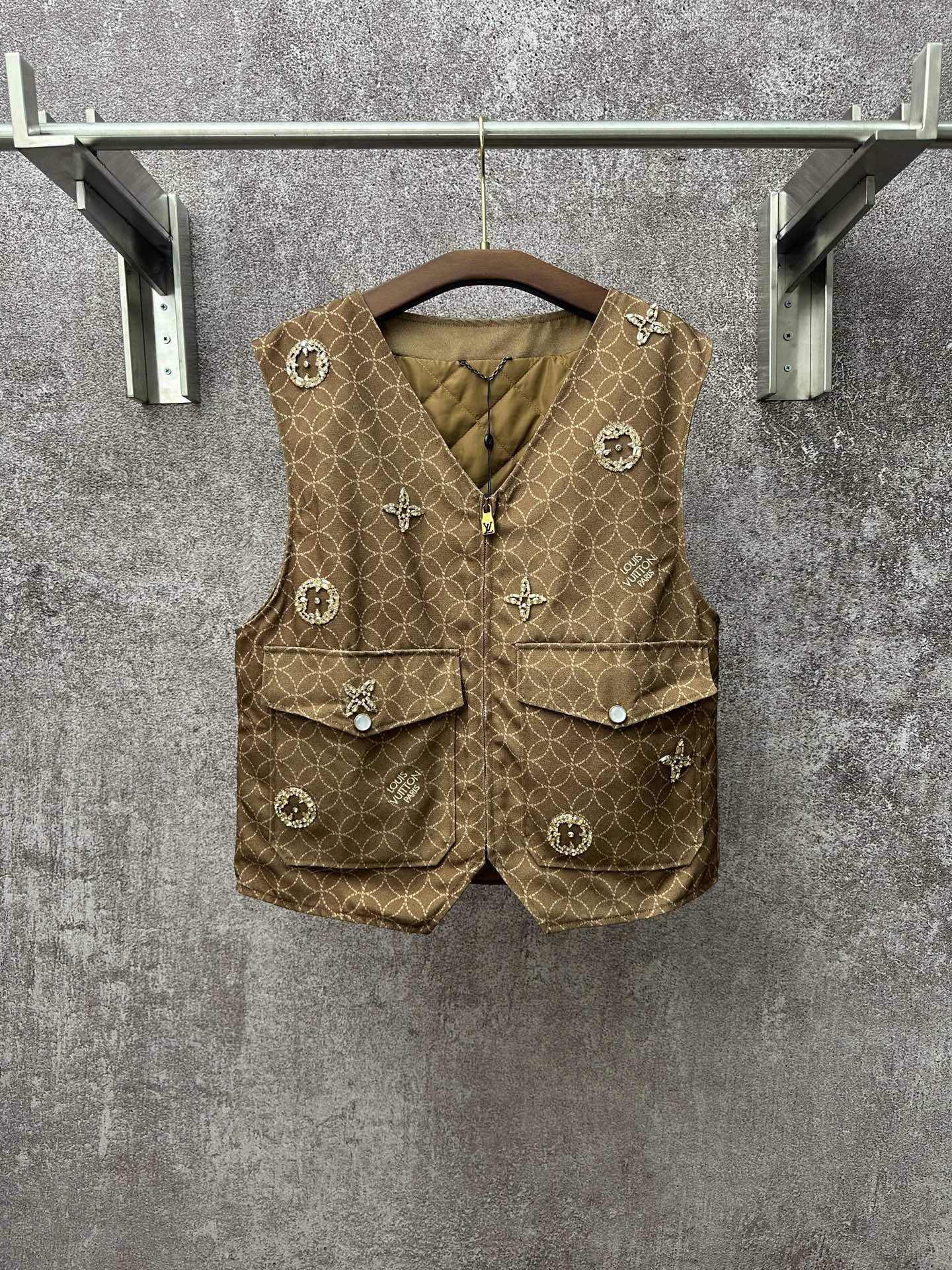 Gold monogram sleeveless vest with zip front, flap pockets, decorative charm buttons