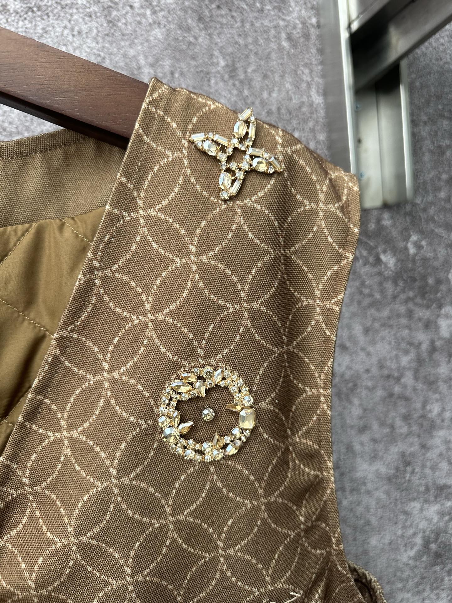 Gold monogram sleeveless vest with cross-shaped charm and decorative circular medallion