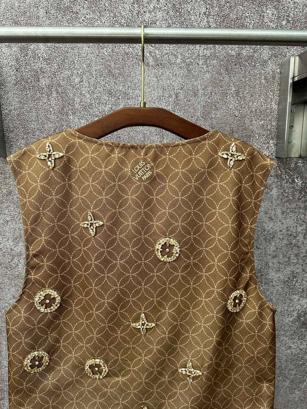 Gold monogram sleeveless vest with decorative medallions, back view on hanger